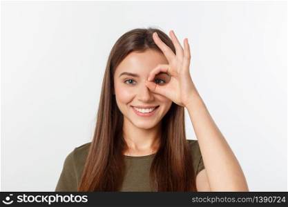 Young woman with ok sign on eye isolate over grey background. Young woman with ok sign on eye isolate over grey background.