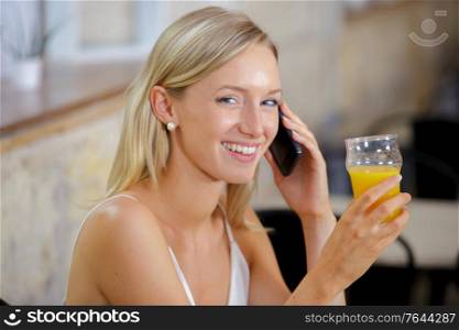 young woman with orange juice and smart phone