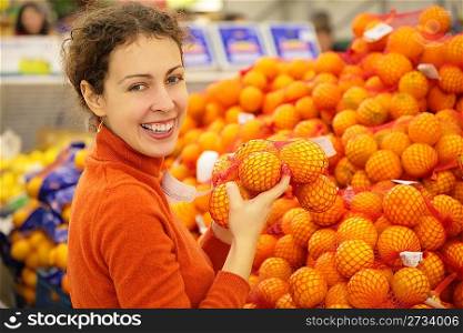 young woman with oranges in store