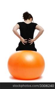young woman with pain in the back. young woman with pain in the back sitting on orange exercise ball