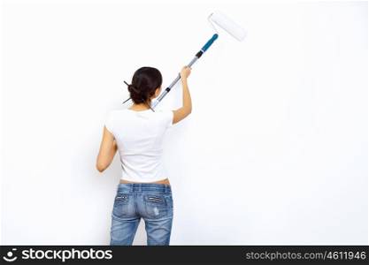 Young woman with paint brushes doing renovation and white wall