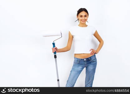 Young woman with paint brushes doing renovation and white wall