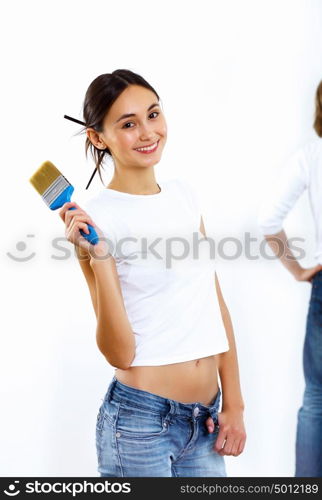 Young woman with paint brushes doing renovation and white wall