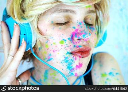 Young woman with paint in her face is listening to music