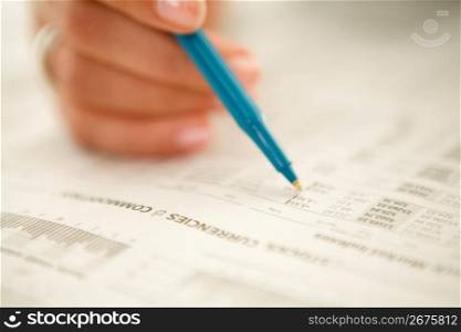 Young woman with pen, looking at stock market data