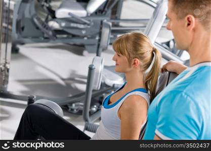 Young woman with personal trainer exercise legs at gym