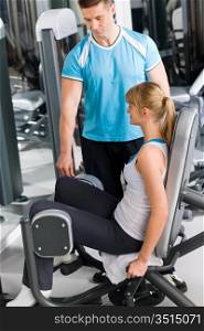Young woman with personal trainer exercise legs at gym