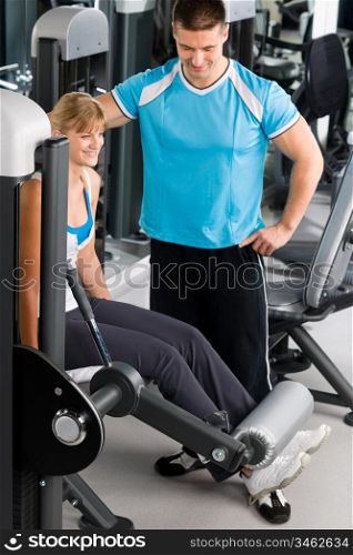 Young woman with personal trainer look at exercise chart at gym