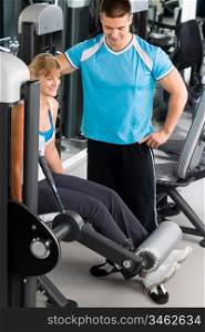 Young woman with personal trainer look at exercise chart at gym