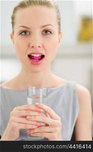 Young woman with pill in mouth