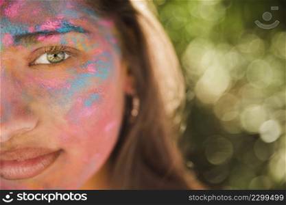 young woman with pink blue holi color her face
