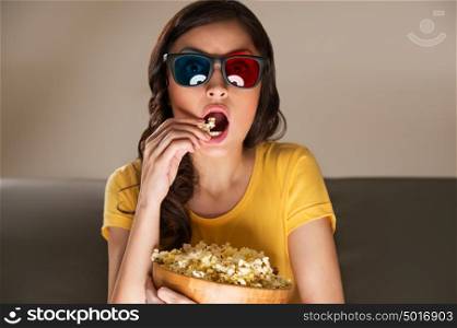 Young woman with popcorn and 3d glasses watching movie at home