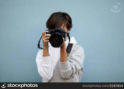 young woman with professional camera, selective focus on nearest part of lens