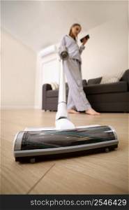Young woman with rechargeable vacuum cleaner cleaning at home. girl is using cellphone. Young woman with rechargeable vacuum cleaner cleaning at home. girl is using cellphone.