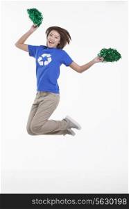 Young woman with recycling t-shirt cheering with pompoms, studio shot