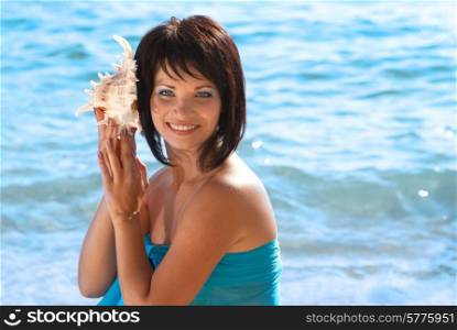 Young woman with seashell on the sunny beach