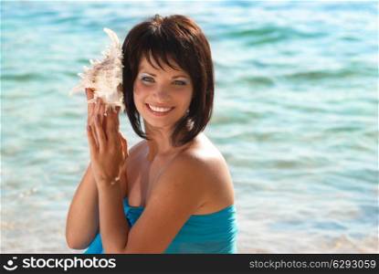 Young woman with seashell on the sunny beach