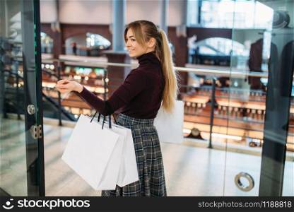 Young woman with shopping bags in mall. Shopaholic in clothing store, consumerism lifestyle, fashion, attractive lady purchasing in the shop. Young woman with shopping bags in mall