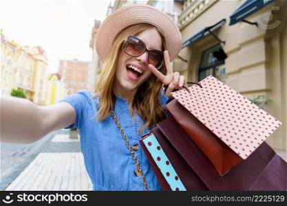 Young Woman with shopping bags making selfie walking in a city at summer day.. Young Woman with shopping bags making selfie walking in a city at summer day