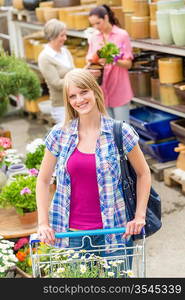 Young woman with shopping cart buying flowers at garden centre