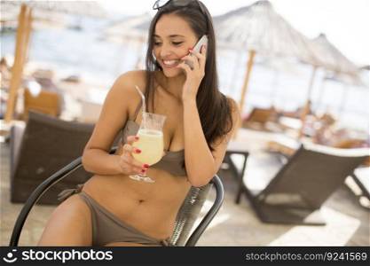 Young woman with smart pho≠on the beach