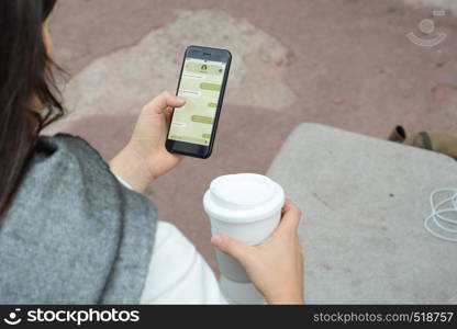 Young woman with smartphone sending text message on mobile app. Social network concept. All screen graphics are made up by us