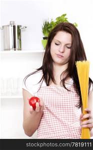 young woman with spaghetti and tomato. young woman holding spaghetti and tomato looking at the tomato
