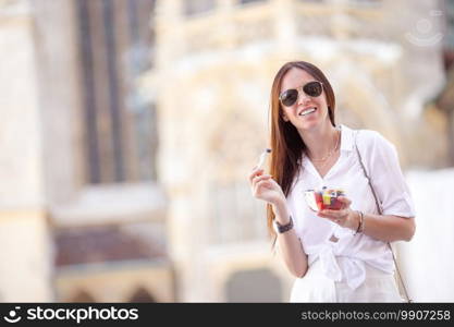 Young woman with street food in Vienna. Beautiful girl with fruits outdoors. Tourist girl enjoying vacation in Vienna and looking at the beautiful horses in the carriage