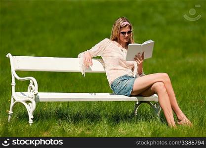 Young woman with sunglasses sitting on white bench; shallow DOF