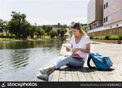 young woman with tablet campus near lake