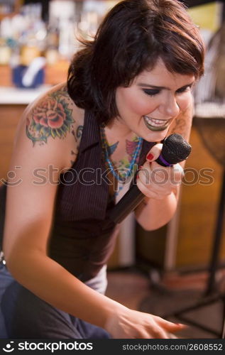 Young woman with tattoos singing at bar