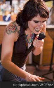 Young woman with tattoos singing at bar