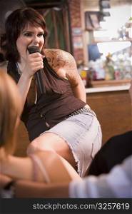Young woman with tattoos singing at bar
