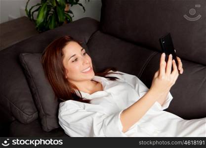 Young woman with the mobile on the sofa at home