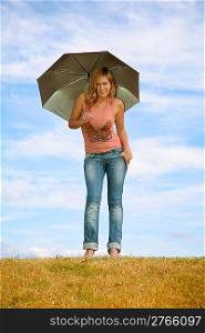 young woman with the umbrella on to the meadow