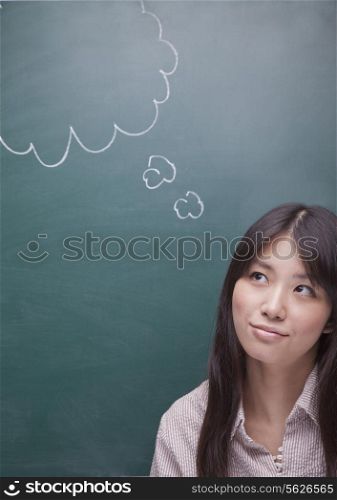 Young woman with thought bubble on blackboard