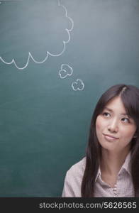 Young woman with thought bubble on blackboard