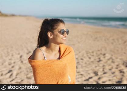 young woman with towel sandy beach