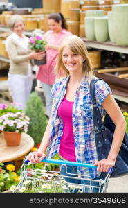 Young woman with trolley shopping for flowers at garden centre