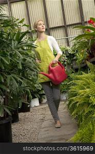 Young woman with watering can in greenhouse