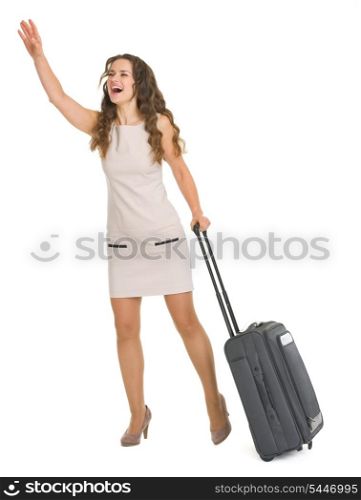 Young woman with wheels suitcase catching taxi