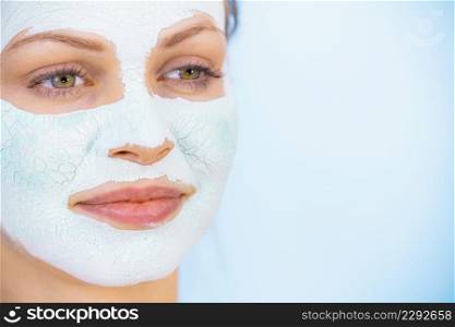 Young woman with white dry mud mask on face, against blue. Teen girl taking care of oily skin, cleaning the pores. Beauty treatment. Skincare.. Girl with dry white mud mask on face
