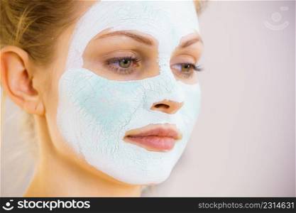 Young woman with white green mud mask on her face. Teen girl taking care of oily skin, cleaning the pores. Beauty treatment. Skincare.. Girl with white green mud mask on face