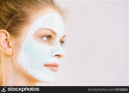 Young woman with white green mud mask on her face. Teen girl taking care of oily skin, cleaning the pores. Beauty treatment. Skincare.. Girl with white green mud mask on face