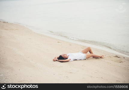 Young woman with white t-shirt lying down on the beach. Smiling enjoy with natural. Women lifestyle concept.