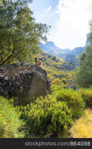 Young woman woman meditating and doing yoga on a sunny bright day. Incredibly beautiful landscape. On background forest.