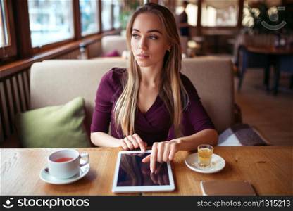 Young woman work on tablet pc using wifi in cafe.
