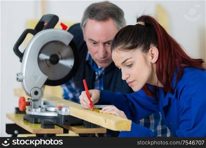 young woman working at carpenter shop with her teacher