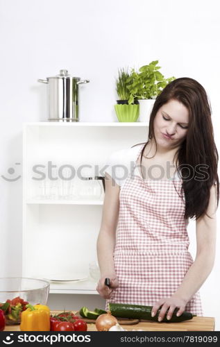 young woman working on a cucumber. young woman is not happy about the working in her kitchen