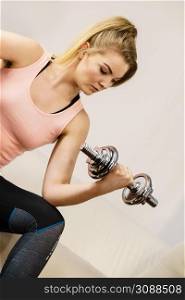 Young woman working out at home with heavy dumbbells. Training at home, being fit and healthy.. Woman working out at home with dumbbell